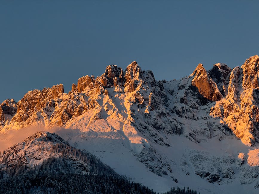 Beautiful snowy mountain peaks illuminated by warm sunrise light.